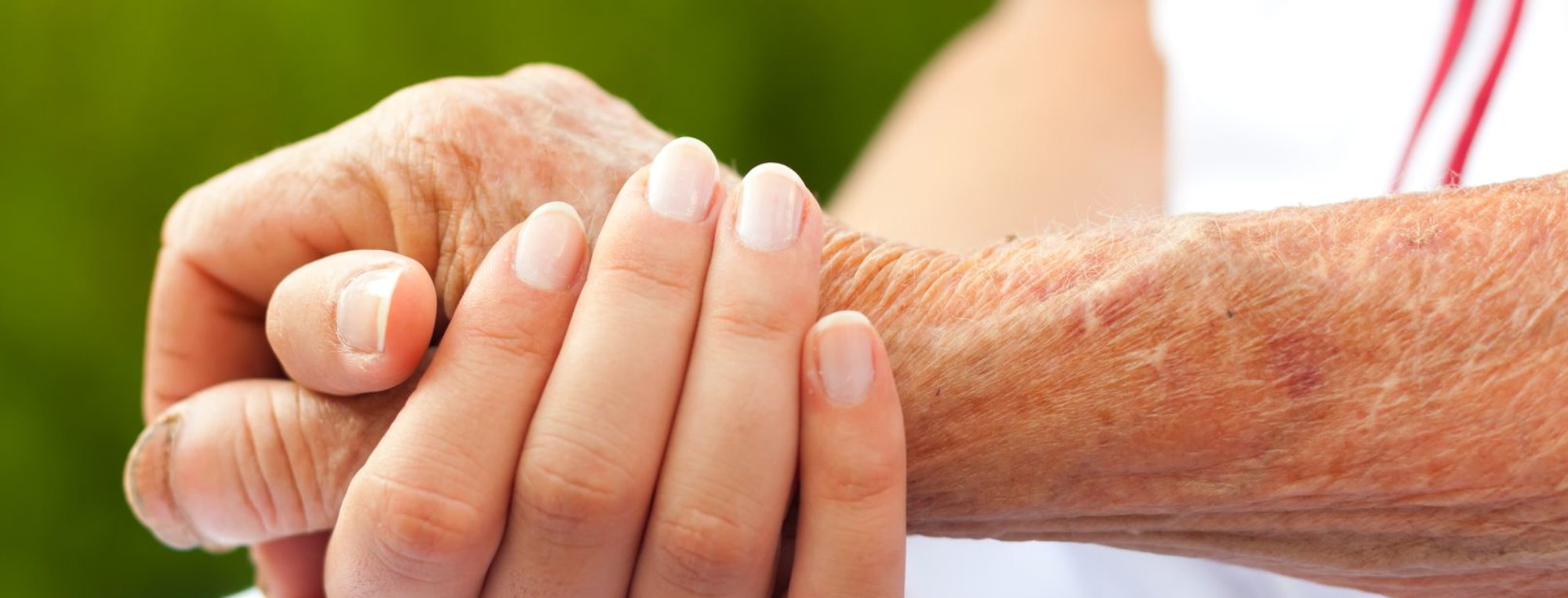 caregiver and senior holding hands