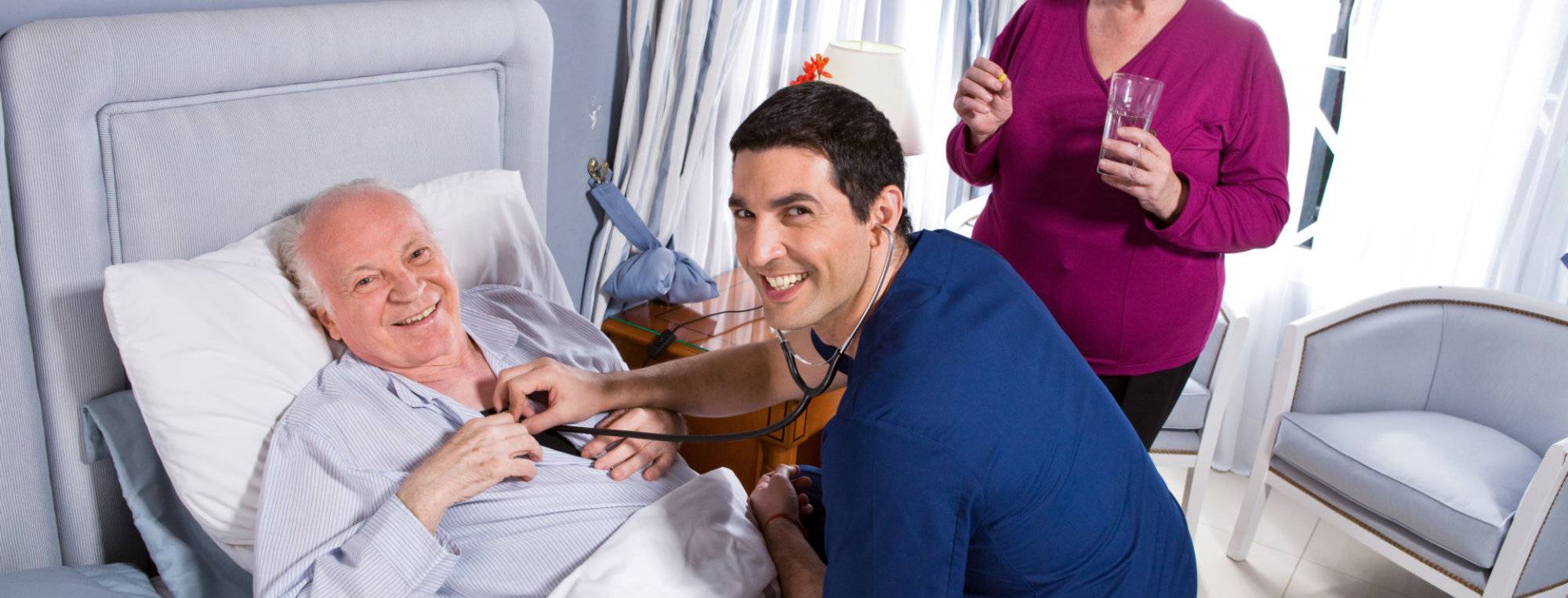 caregiver checking the measure of heartbeat of senior man on the bed